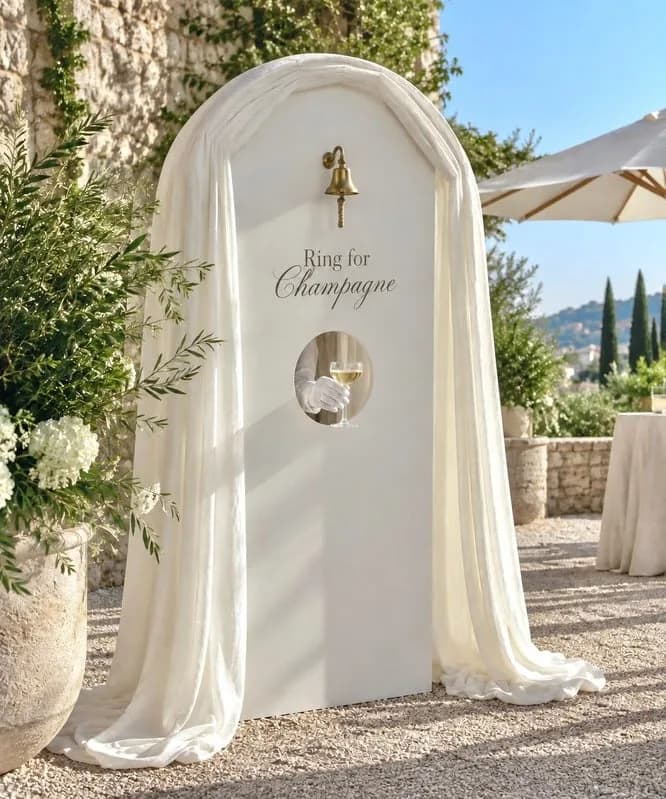 A draped champagne wall with a round serving hatch