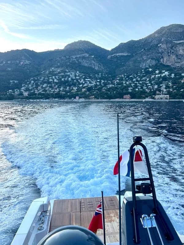 The wake behind a yacht running along a hilly coast